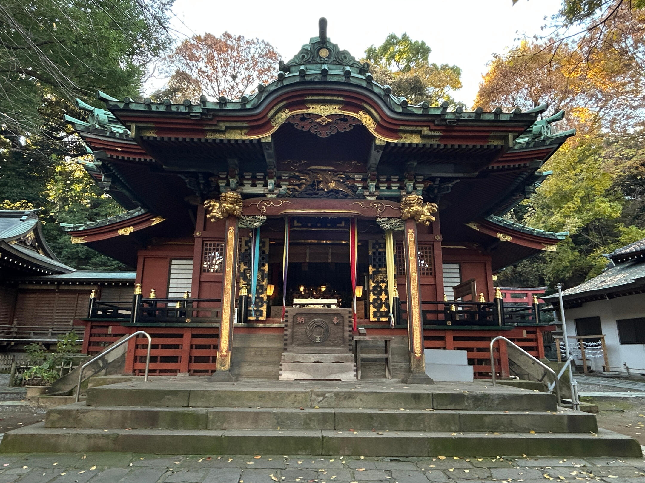 Ooji Inari Srhing in the fall. Red shrine building with gold accents and tile roof.